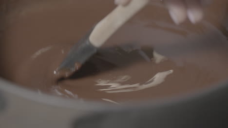 stirring fluid chocolate inside a cooking pot while its heating in slowmotion log