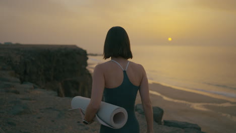 woman practicing yoga at sunset on a beach cliff