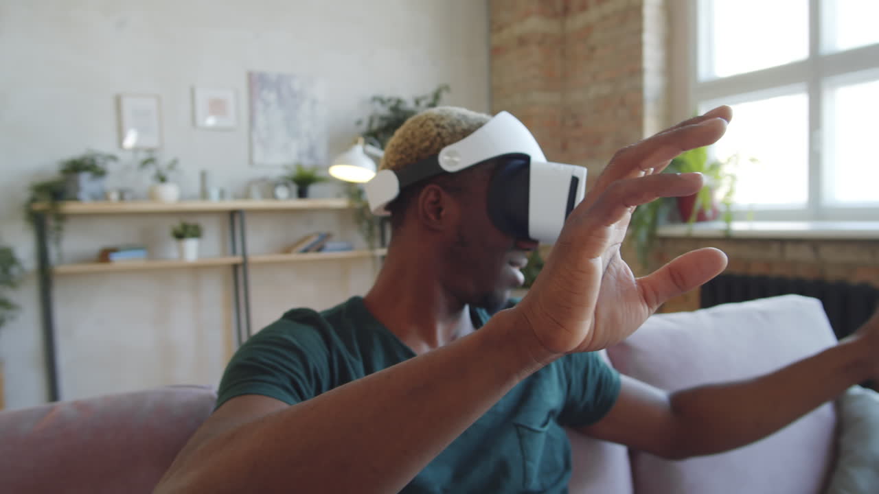 hombre negro sonriente usando gafas vr en casa