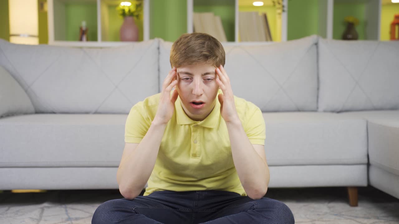 The young man is upset, overwhelmed and constricted.