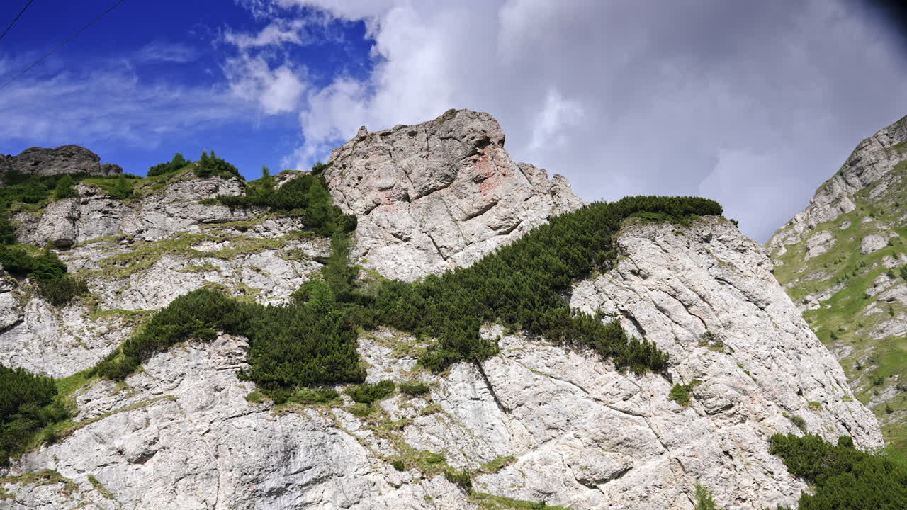 Approaching the white cliff rock with some greenery on top. Scenic ride by the cable car road in Busteni, Romania