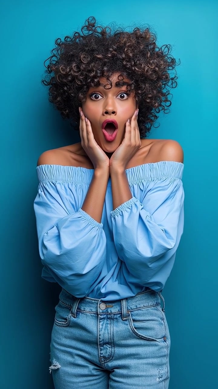 Giovane donna gioiosa con capelli ricci che ride e indica la telecamera su uno sfondo blu.