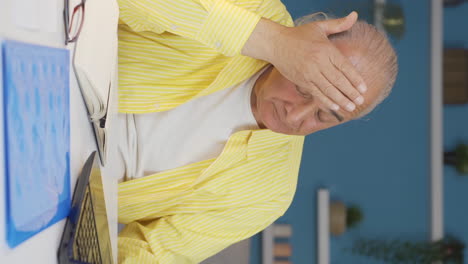 Vertical-video-of-Home-office-worker-old-man-is-tired-and-sleepy.