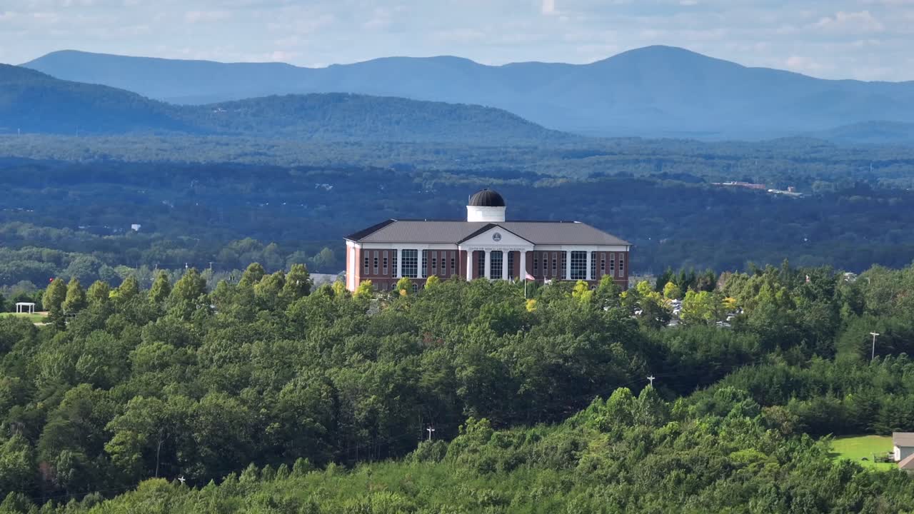 Liberty university college of osteopathic medicine on of Mountain in Lynchburg, Virginia. Aerial wide shot. Patriotic flag of USA waving on flagpole. Sunny summer day with Green landscape in back