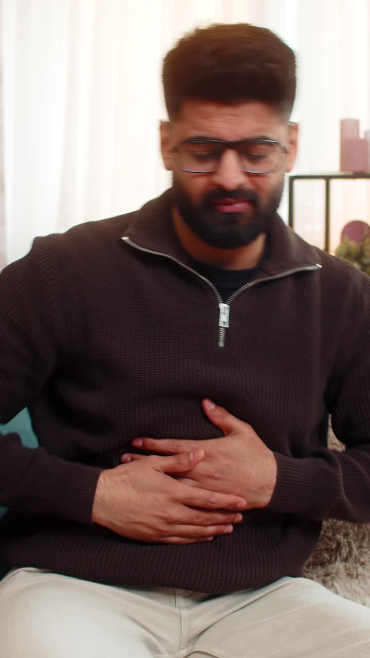Indian man holding stomach at home with visible pain nausea and discomfort from food poisoning