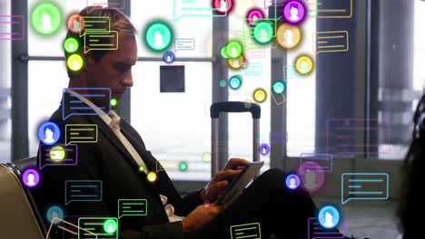 animation of profile and message icons over caucasian businessman using digital tablet at an airport