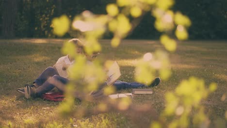 children with books and schoolbags do home task in park