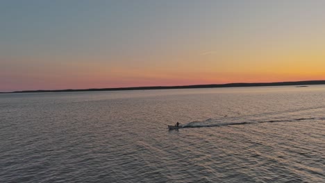 a boat travelling across the water during sunset