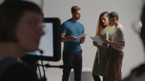 vista trasera del equipo de filmación filmando una película o video en el estudio con la directora hablando con los actores en el ensayo 3
