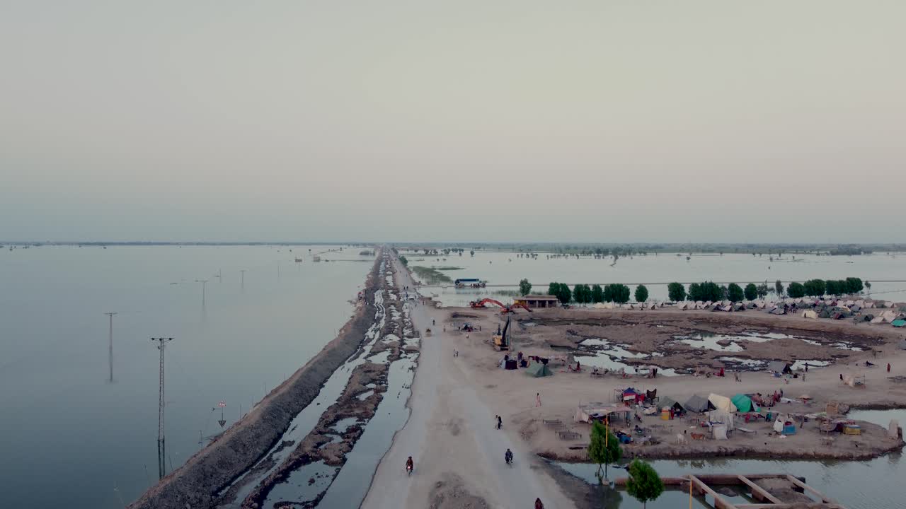 vista de una pequeña carretera rodeada de campos inundados que se adentra en el horizonte en sindh