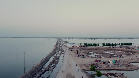 view of small road surrounded by flooded fields going off into horizon in sindh