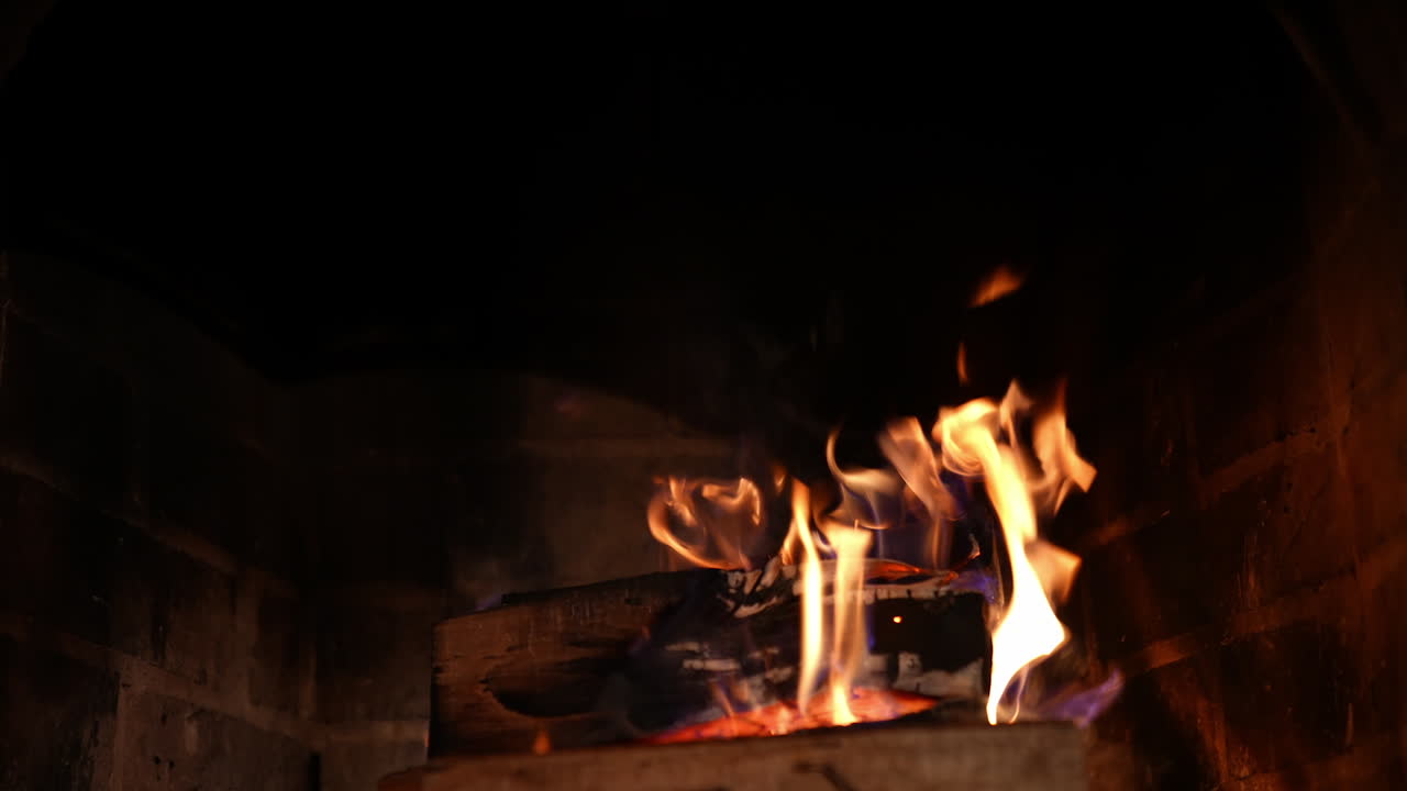 Wood burning in stone fireplace. Burning fireplace. Glowing fire in the stone fireplace to warm at night. Cozy evening near the fire at home at winter holidays.