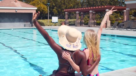 Amigos-En-La-Piscina,-Sentados-En-El-Borde-Y-Saludando-Con-Las-Manos,-Concepto-De-Amistad-Interracial