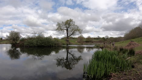 Un-Cielo-Nublado-Moviéndose-Por-El-Campo-Que-Rodea-Una-Pequeña-Piscina-De-Pesca-Con-Mosca-En-Un-Día-Ventoso-En-Worcestershire,-Inglaterra