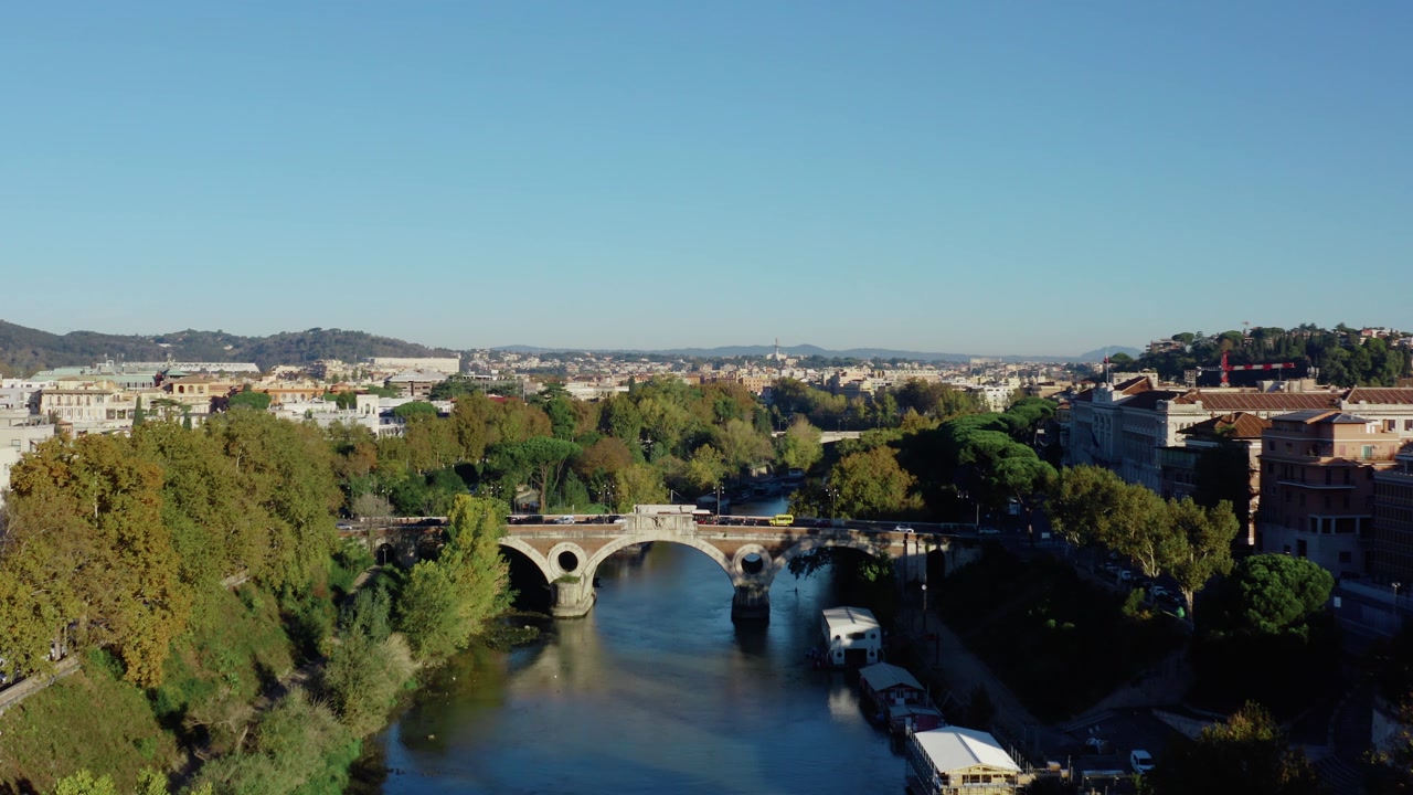 Aerial Drone View of Historic Rome Cityscape with Bridge over Tiber River, Traffic, Autumn Trees and Iconic Skyline under Bright Morning Sun in Italy.