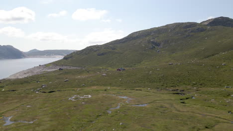 aerial shot flying low over mountainous terrain towards a cabin in norway