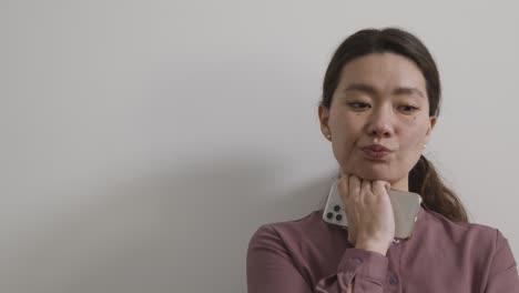 female candidate wearing suit in office waiting for job interview holding mobile phone