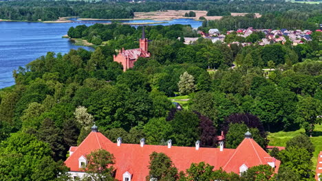 birzai castle and church in background by sirvena lake. aerial view