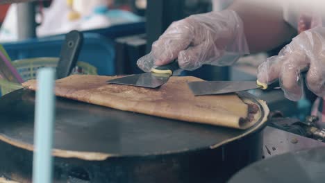 skilled chef folds made pancake on crepe maker in cafe