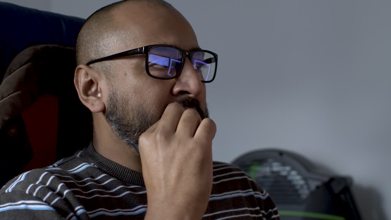 A middle-aged man is having a snack in front t of his computer