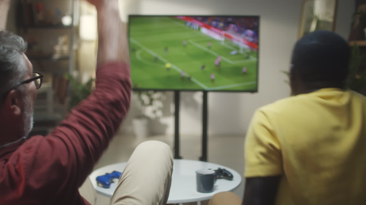 Due uomini che guardano e reagiscono a una partita di calcio in TV