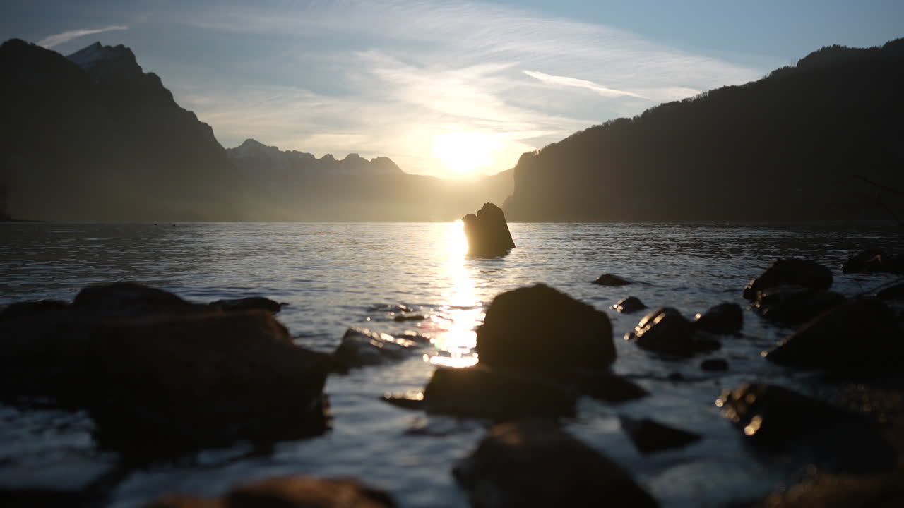 Golden hour over Walensee lake with mountain silhouettes in Switzerland