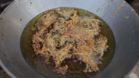 top view of deep-fried enoki mushroom or golden needle mushroom floating on hot boiling oil in big frying pan at food stall street market