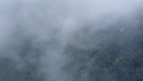 a breathtaking aerial drone shot captured from above a layer of clouds, providing a unique vantage point of catarata del toro in costa rica