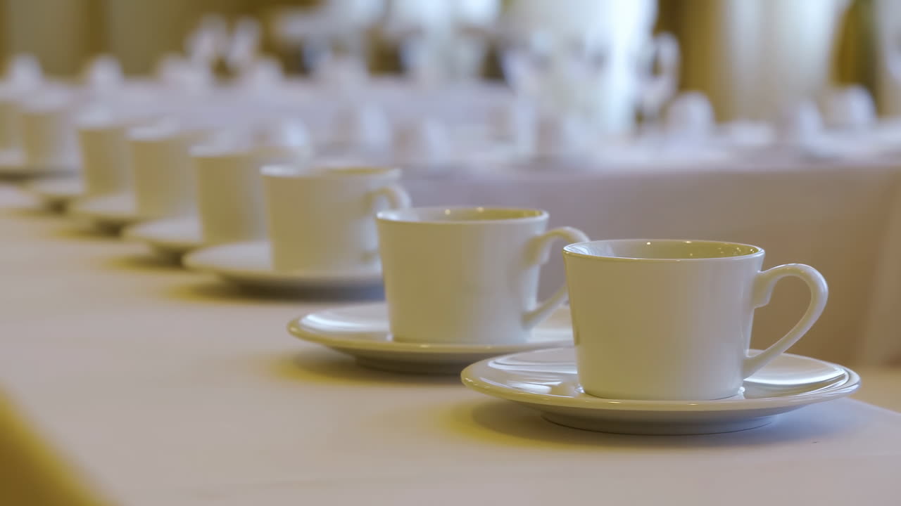 Neatly Arranged White Coffee Cups and Saucers on a Table