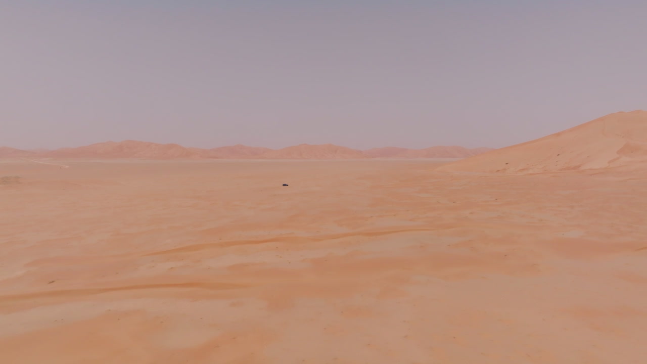 Car in desert landscape with vast, empty dunes in the Empty Quarters of Oman
