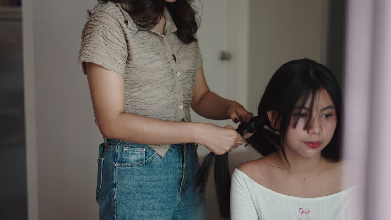 Young Asian Woman Braiding Another Woman's Long Hair