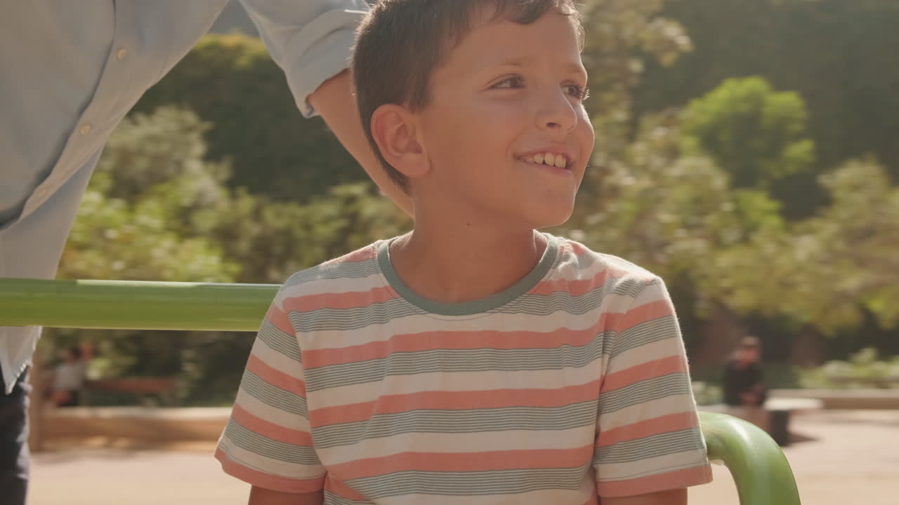 Niño sonriendo y mirando a su alrededor en un parque infantil soleado