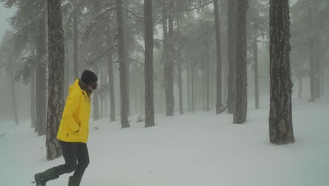 un hombre camina solo por un bosque blanco y nevado mientras usa una chaqueta amarilla brillante