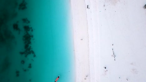smooth aerial flight bird's eye view top drone shot over white sand blue water wave and people