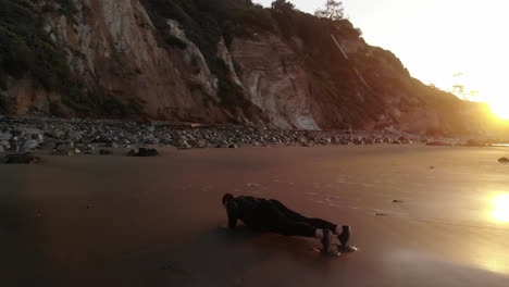 Un-Hombre-Musculoso-Fuerte-Haciendo-Flexiones-Para-Un-Entrenamiento-De-Fitness-Matutino-Al-Amanecer-En-Una-Playa-En-Santa-Barbara,-California