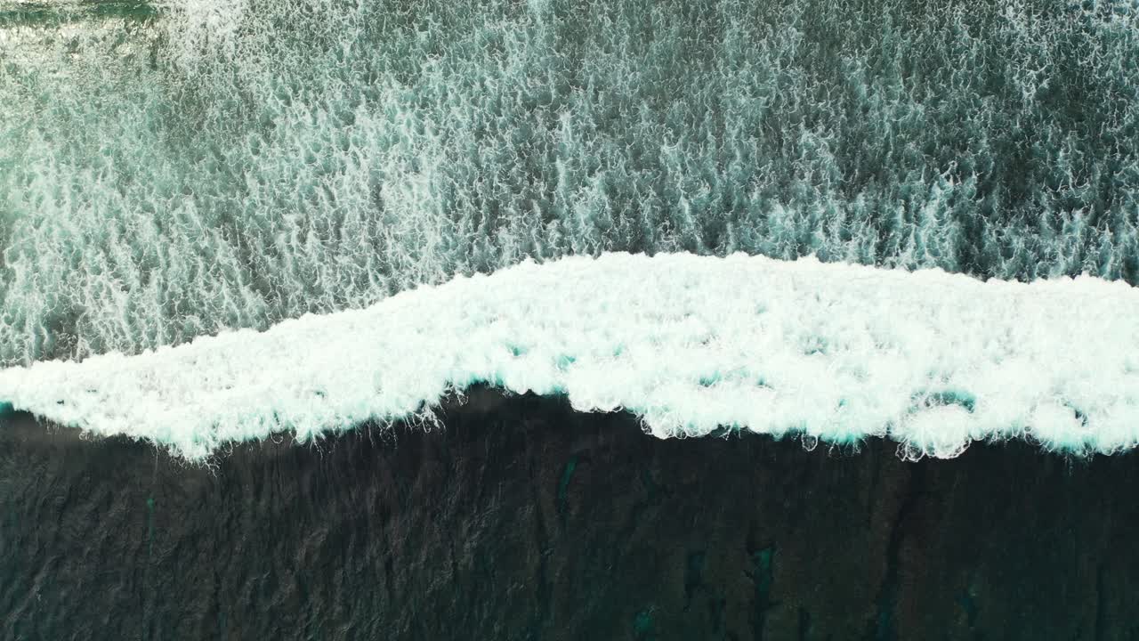 Beautiful white waves of deep dark ocean splashing and foaming on exotic beach, sea texture seen from above, copy space