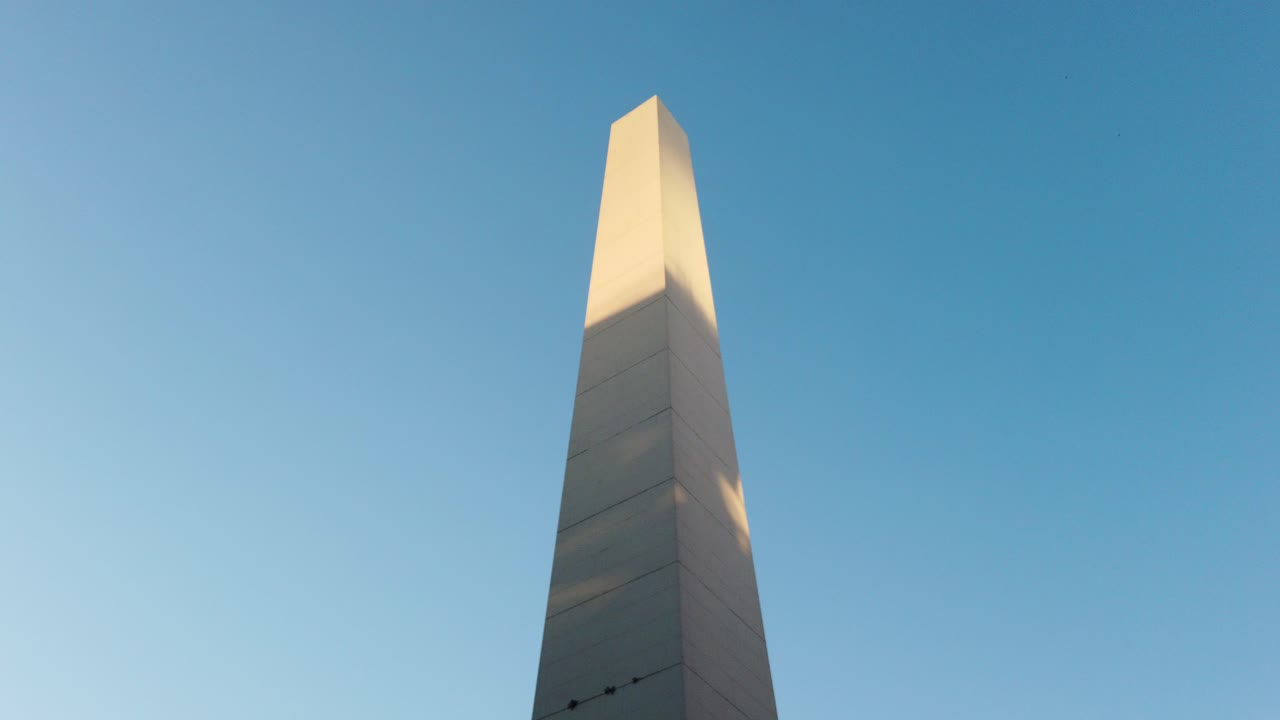 Closeup of the Obelisk in Buenos Aires, an iconic historic landmark rising against a clear blue sky, static upward angle