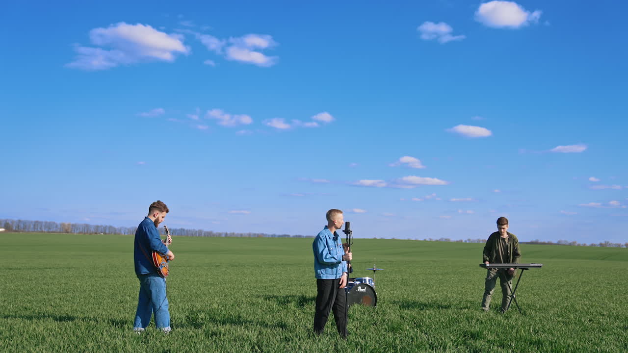Musical band playing on grass. Group of young people playing instruments on field