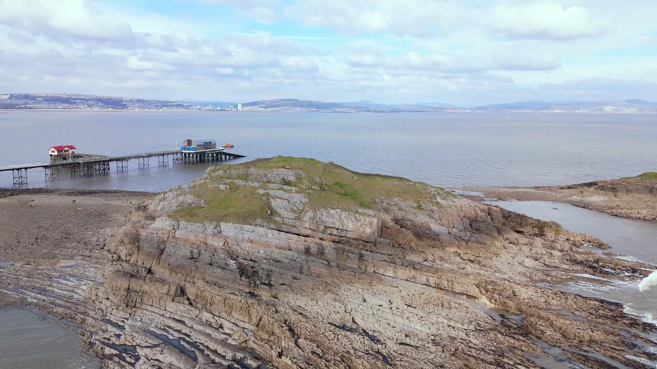 Mumbles Lighthouse situated at rocky terrain near Swansea in United Kingdom. Drone view.