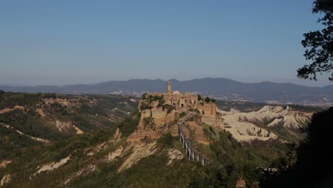 static wide shoot for the dying town civita di bagnoregio in italy on top of the mountain with a walking bridge full of tourists