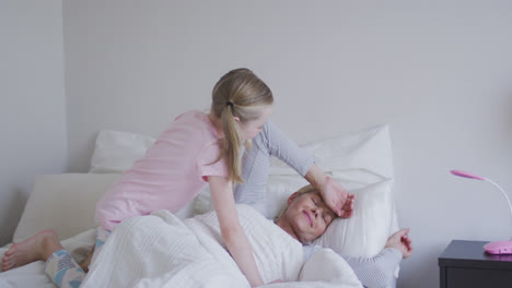 Side-view-of-Caucasian-girl-waking-up-her-mother-on-bed-