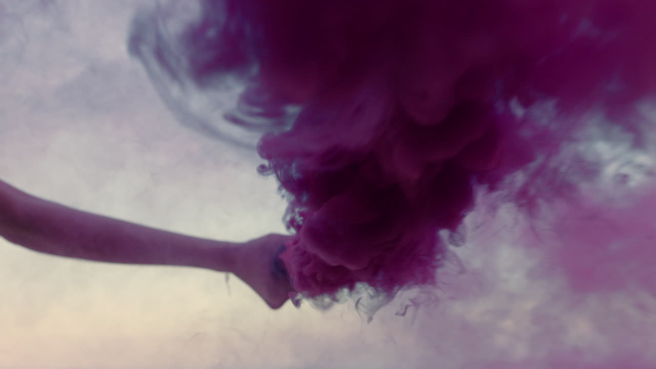 beautiful woman waving pink smoke bomb dancing on beach at sunrise celebrating creative freedom
