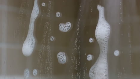 soap suds and water droplets on glass shower door