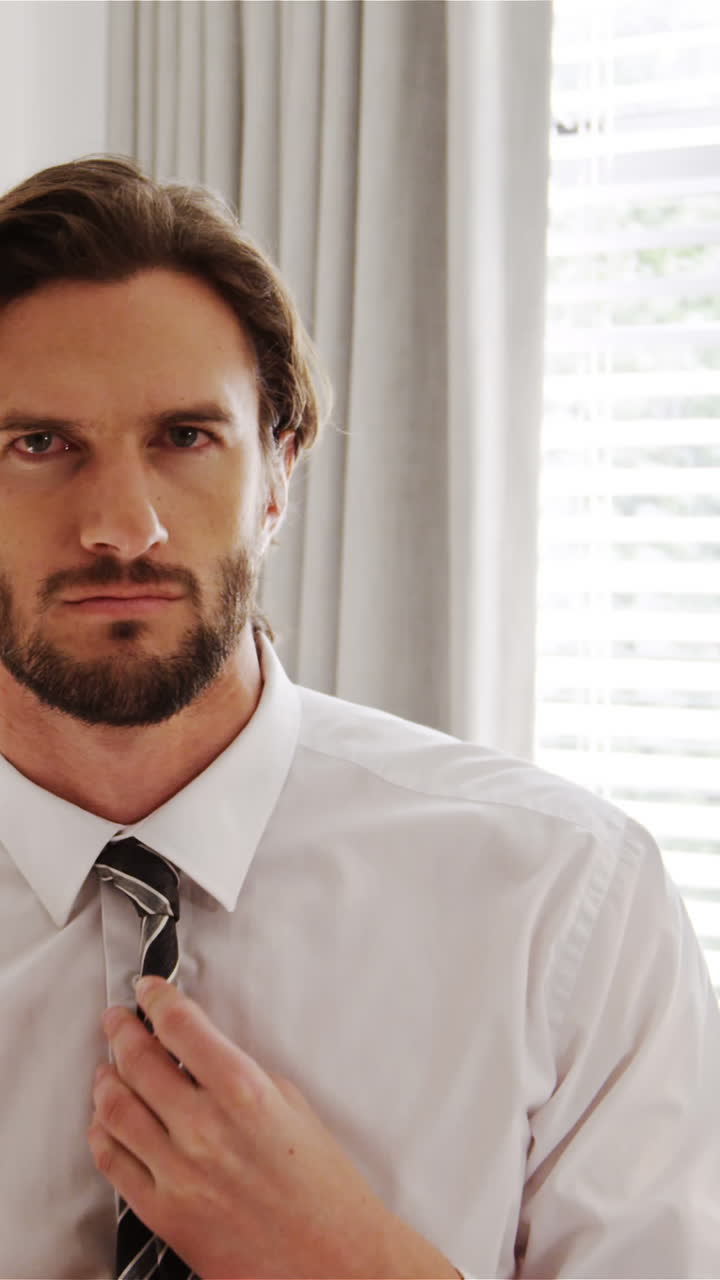 hombre ajustando una corbata en el dormitorio