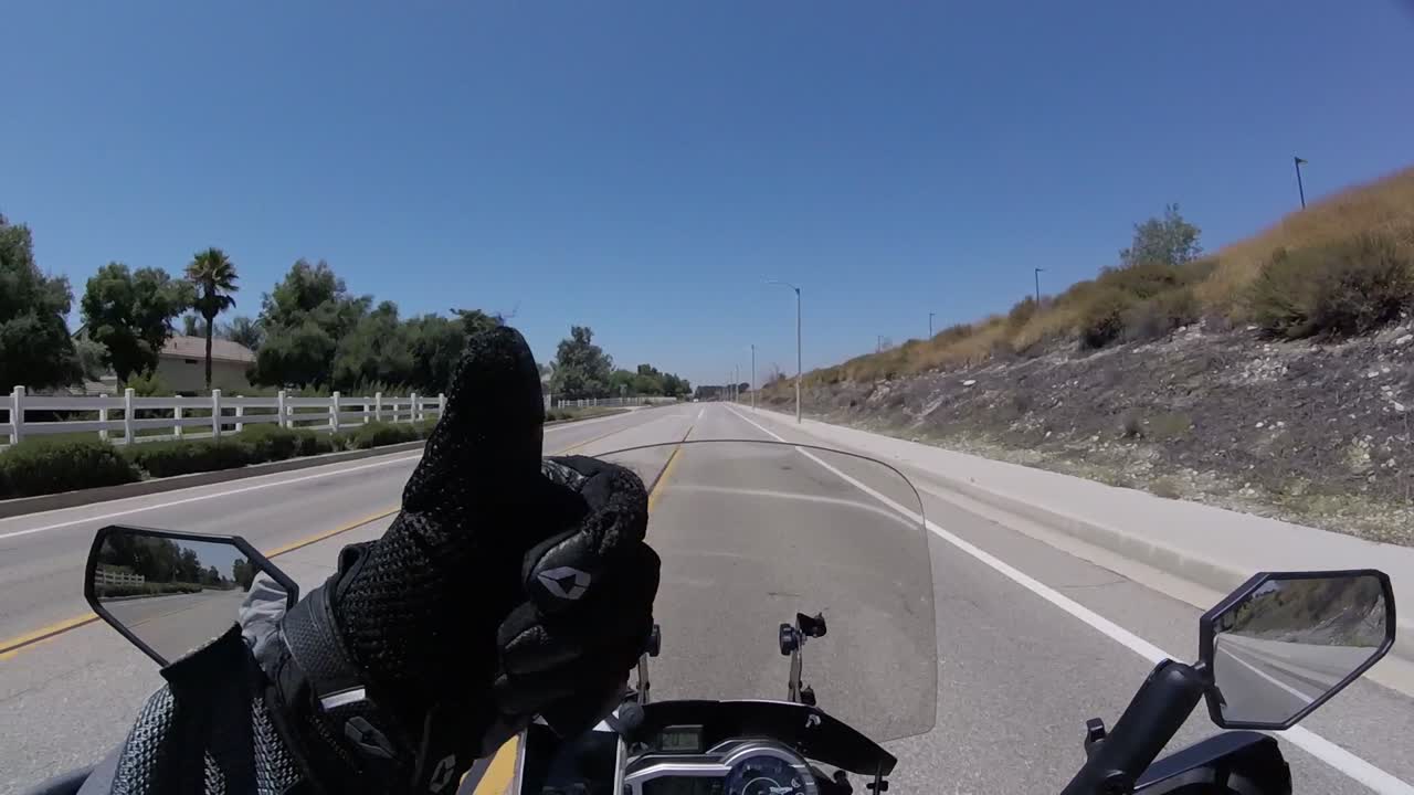 Rider driving fast motorbike on highway showing thumb up POV