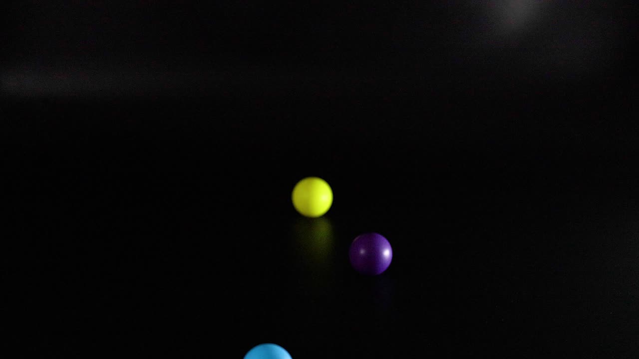 múltiples bolas de colores rebotando contra un fondo oscuro