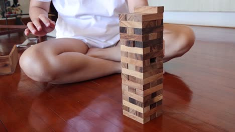 person playing jenga, removing and stacking blocks.