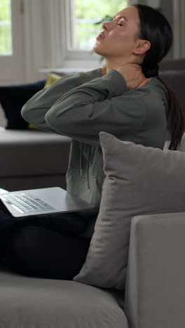 video vertical de una mujer ansiosa sentada en el sofá trabajando desde casa usando una computadora portátil preocupada por la crisis del costo de la vida 1