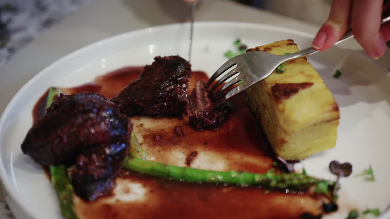 Close up of gourmet steak served with layered potatoes and sauce on a plate