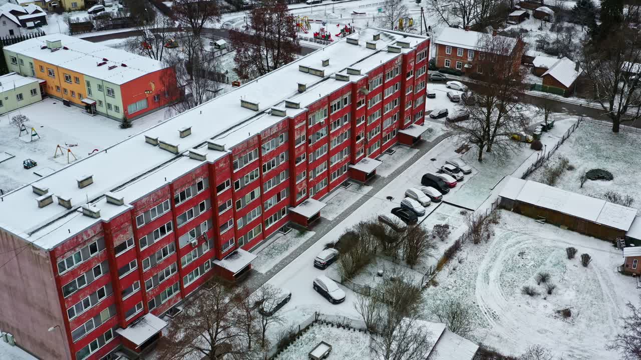 Lumi peittää asuinrakennuksia ja autoja talvella, näkymä kaupunkielämään ylhäältä kuvattuna
